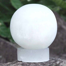 Load image into Gallery viewer, Selenite sphere crystal lamp with soft white glow on stone base – natural wellness light