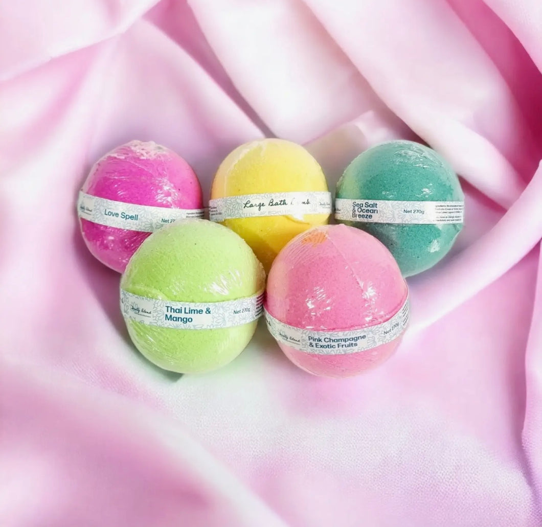 Assorted large bath bombs by Natural Soy Creations in vibrant colours displayed on soft pink fabric background.