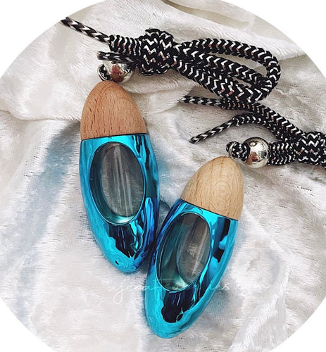 Blue bullet car diffuser with wood top and black-and-white cord, designed for hanging and releasing fragrance in vehicles