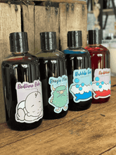 Load image into Gallery viewer, Colourful bottles of handmade bubble bath displayed on wooden surface, vibrant bath additives by A Lil Luxury.
