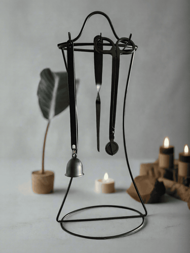 Candle care kit with wick trimmer, snuffer, and dipper tools displayed on a black metal stand.