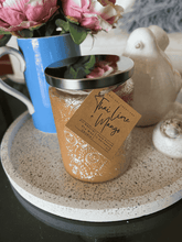 Load image into Gallery viewer, Luxury champagne embossed candle jar placed on a round tray beside pink flowers and decorative home items.
