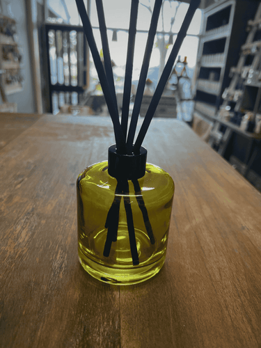 Green glass reed diffuser bottle with black reeds.