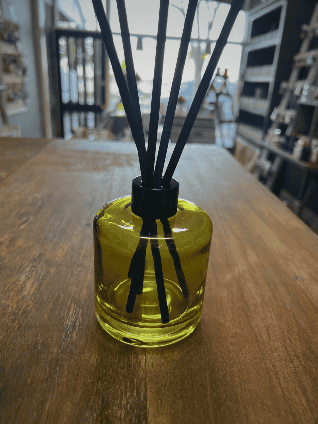 Green glass reed diffuser bottle with black reeds.