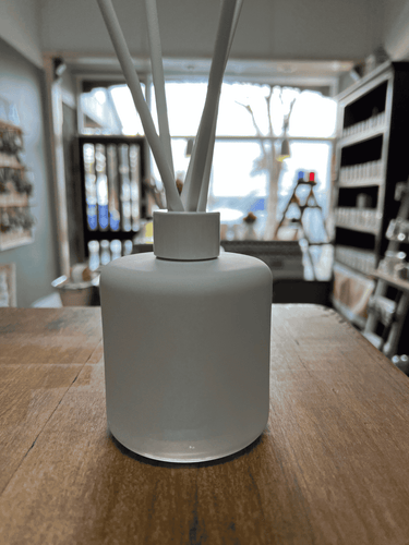 Concrete Grey matte reed diffuser with white reeds on wooden table.