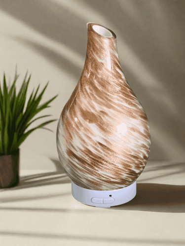 Dubai ultrasonic diffuser with natural wood grain finish, colour-changing LED base and mist output, displayed beside a small plant.