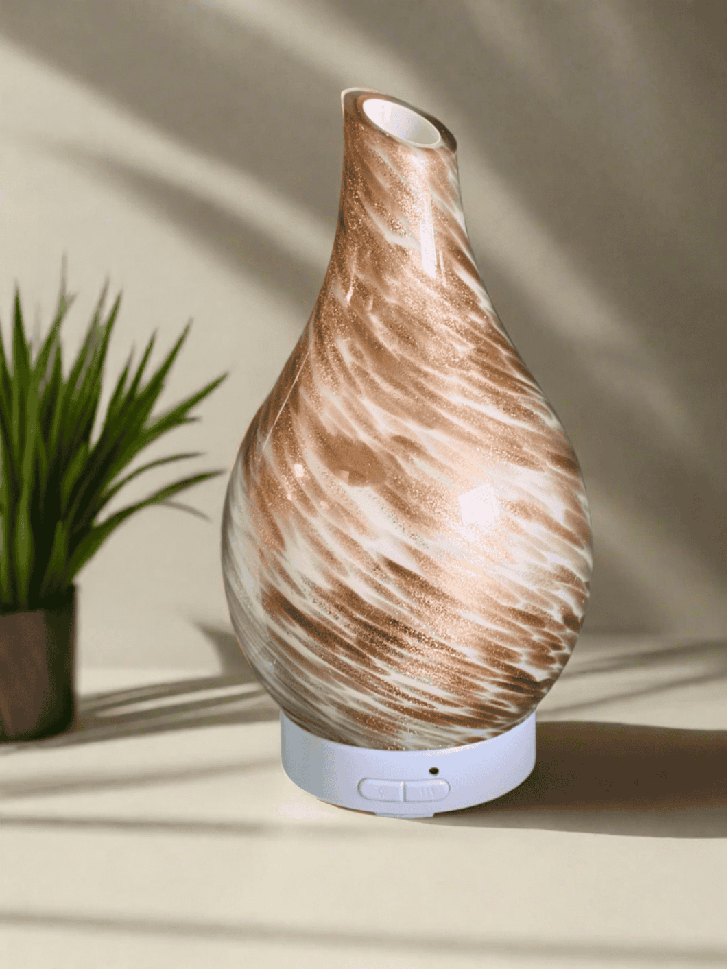 Dubai ultrasonic diffuser with natural wood grain finish, colour-changing LED base and mist output, displayed beside a small plant.