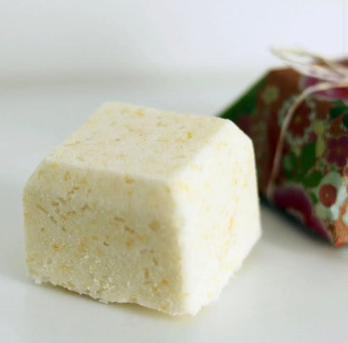 Natural Soy Creations Energise bath bomb in pale yellow, displayed with patterned wrapping on a white surface.