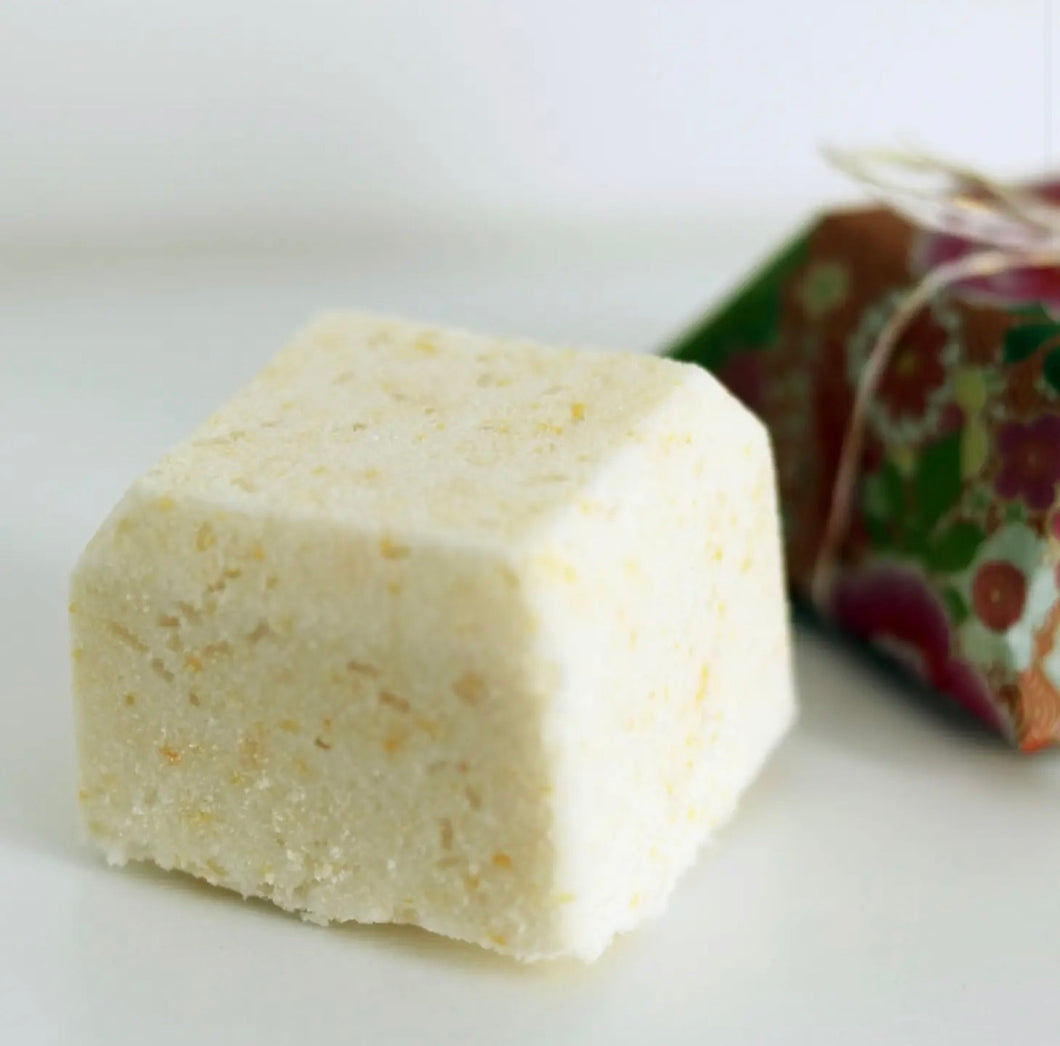 Natural Soy Creations Energise bath bomb in pale yellow, displayed with patterned wrapping on a white surface.