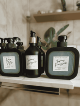 Load image into Gallery viewer, Collection of Natural Soy Creations goats milk hand soaps in black bottles, featuring scents Lemon Myrtle and Japanese Honeysuckle
