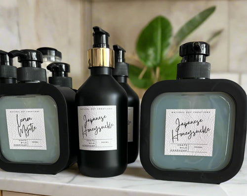 Collection of Natural Soy Creations goats milk hand soaps in black bottles, featuring scents Lemon Myrtle and Japanese Honeysuckle