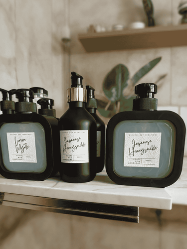Collection of Natural Soy Creations goats milk hand soaps in black bottles, featuring scents Lemon Myrtle and Japanese Honeysuckle