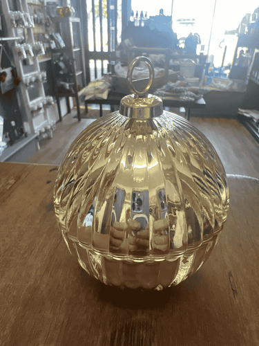 Close-up of a gold mini bauble candle on a wooden surface, reflecting warm ambient light.