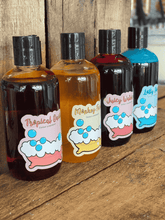 Load image into Gallery viewer, Range of bright, handmade bubble bath bottles lined up on wooden shelf, fun and fragrant bath gift collection.
