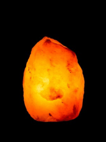 Natural pink Himalayan salt lamp glowing warmly on wooden base, soothing 1.5–2 kg crystal lamp for relaxation.