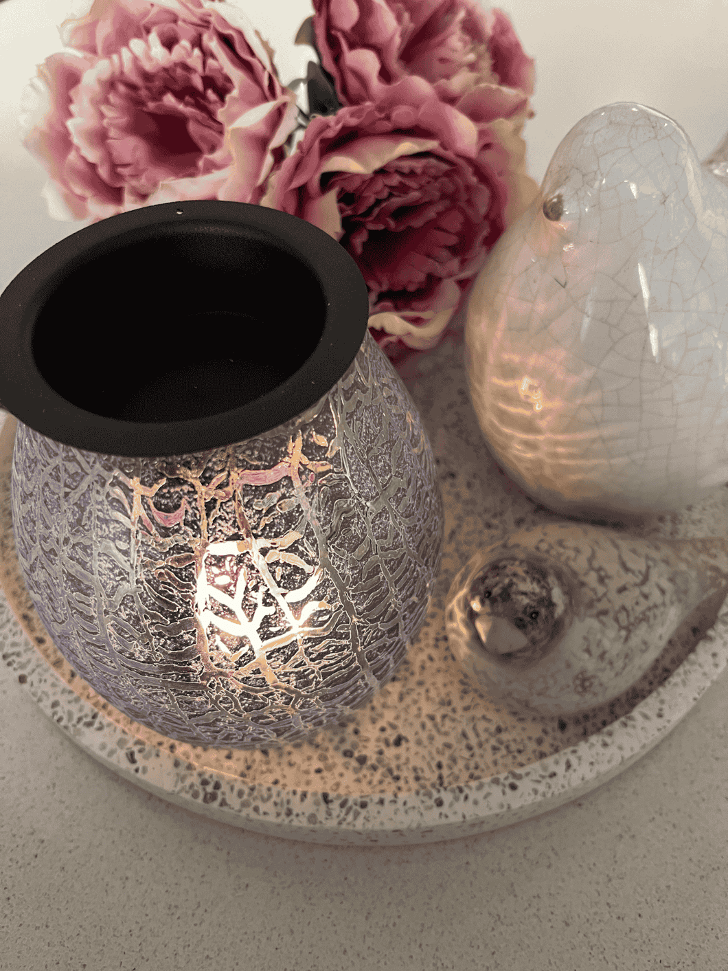 Indigo Alaska electric heat plate wax warmer glowing on a tray beside pink flowers – Natural Soy Creations