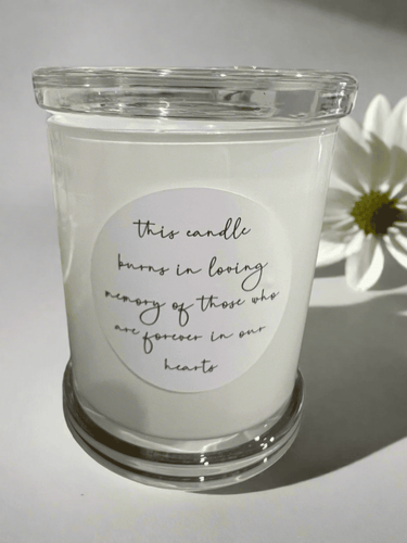 Memorial candle in a clear glass jar with the message: This candle burns in loving memory of those who are forever in our hearts.