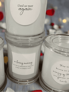 Collection of memorial candles in clear glass jars with messages including Forever in Our Hearts, Until We Meet Again, and In Loving Memory.