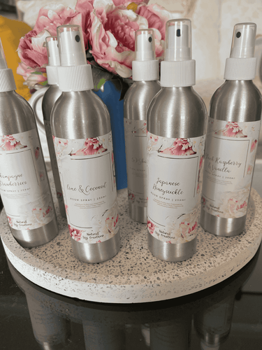 Natural Soy Creations 250ml room sprays in silver bottles with pink labels displayed on a round tray.