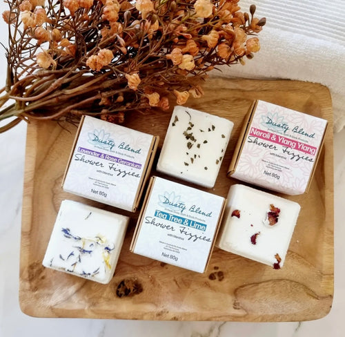 Natural Soy Creations shower fizzies displayed on a wooden tray with dried flowers, assorted essential oil blends.