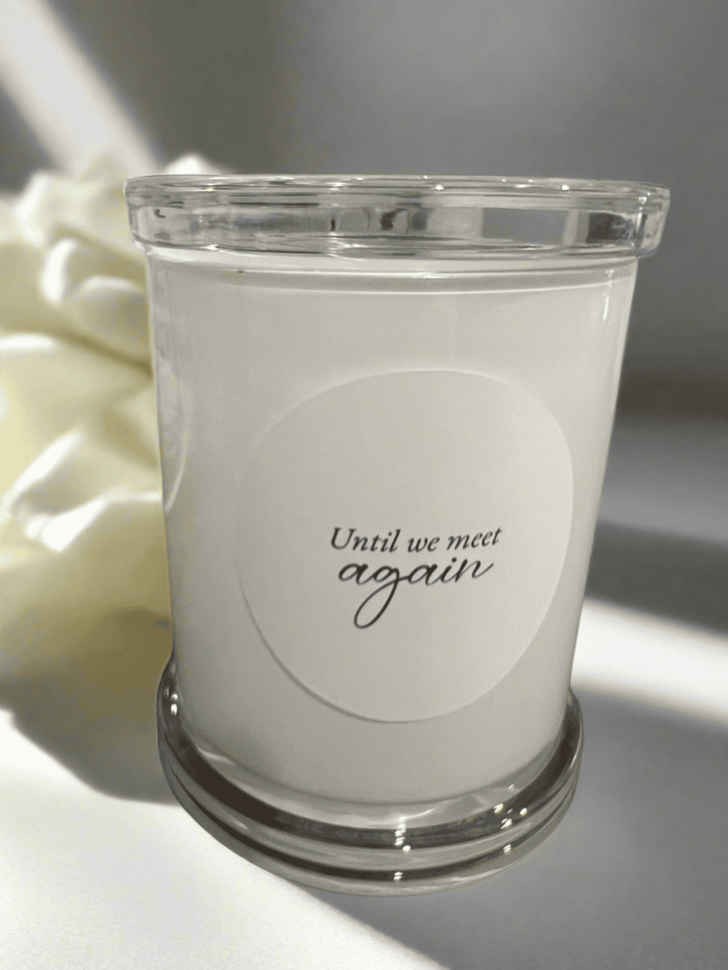 Memorial candle in a clear glass jar with the message: Until we meet again.