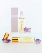 Load image into Gallery viewer, Ethereal crystal-infused perfume rollers by Bopo Women displayed with amethyst crystals and gold caps, natural aromatherapy fragrance.
