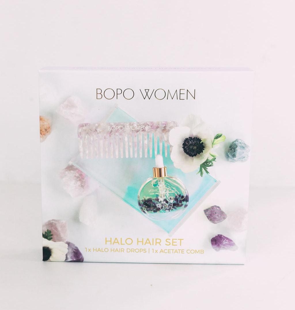 Bopo Women Halo Hair Drops Gift Set with nourishing hair oil, lilac tortoise acetate comb, and gold foil gift packaging, styled with flowers and crystals.