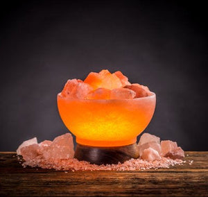 Fire bowl Himalayan salt lamp glowing with salt rocks on wooden table