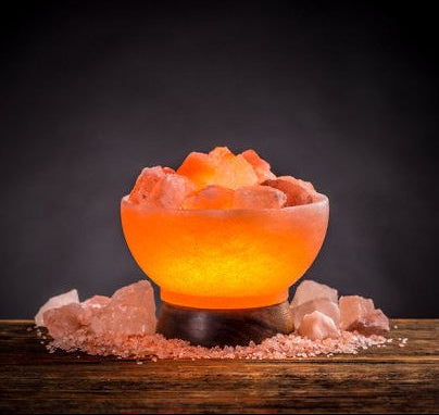 Fire bowl Himalayan salt lamp glowing with salt rocks on wooden table