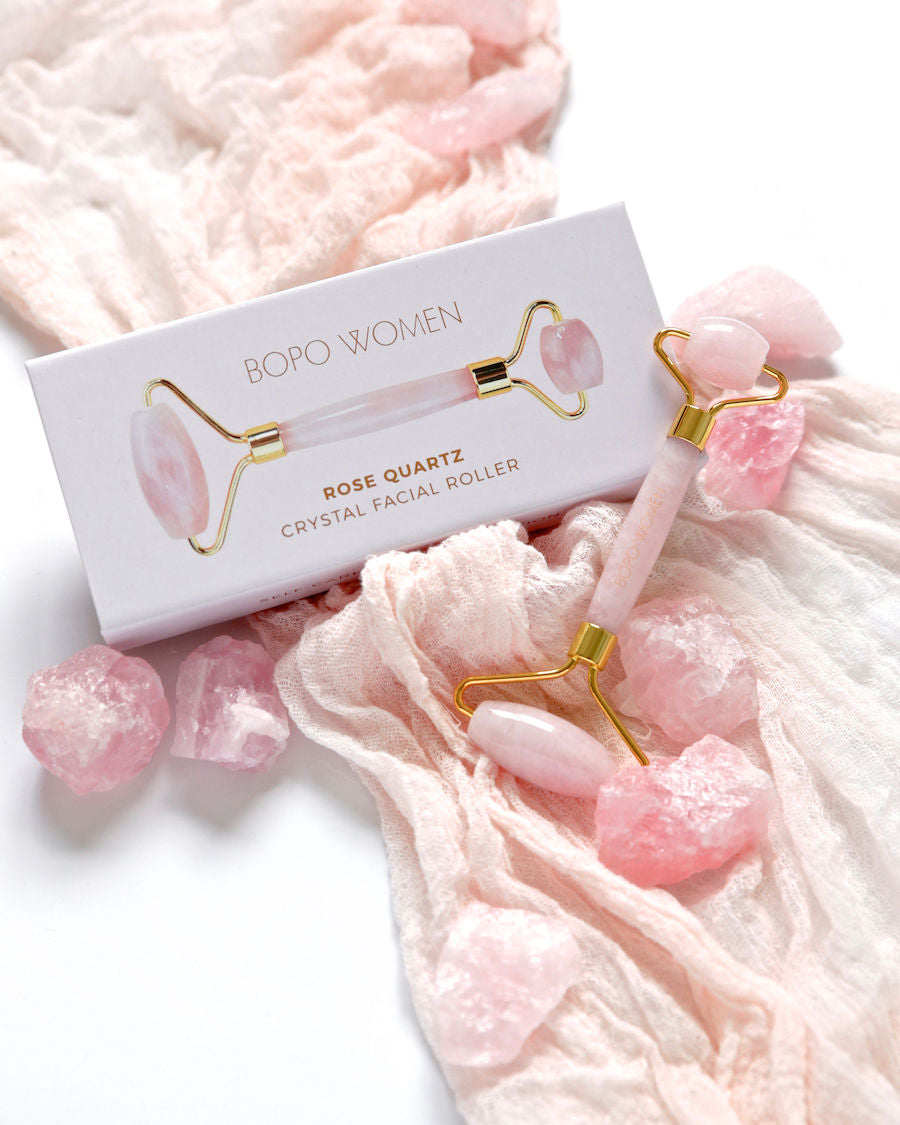 Rose quartz facial roller in gift box on soft fabric, soothing crystal massage tool for skincare and relaxation.